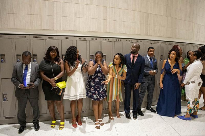 A line of well-dressed graduates smile and chat while waiting in a hallway for Black Graduation to begin.