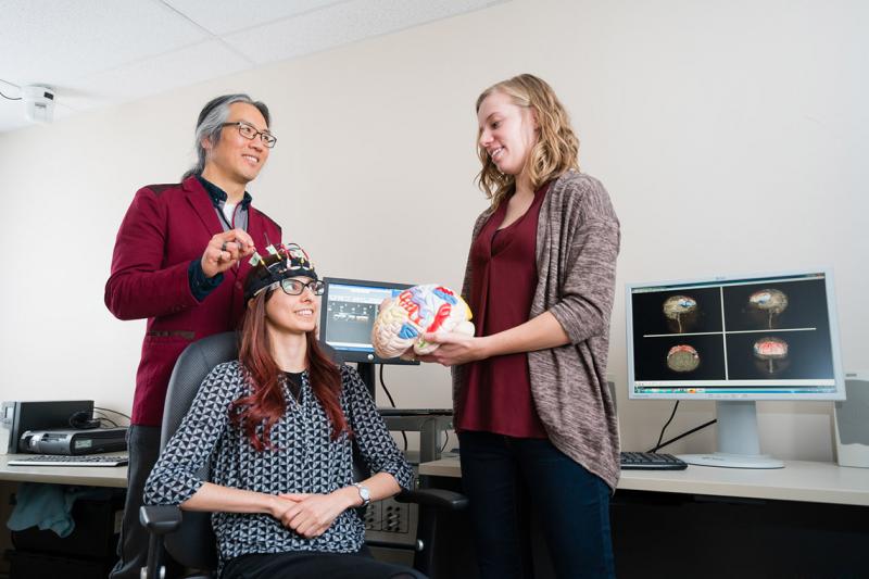 Professor Tom Chau, a University of Toronto pediatric rehabilitation engineer, works with two graduate students to develop a brain-computer interface for children (photo by Neil Ta)