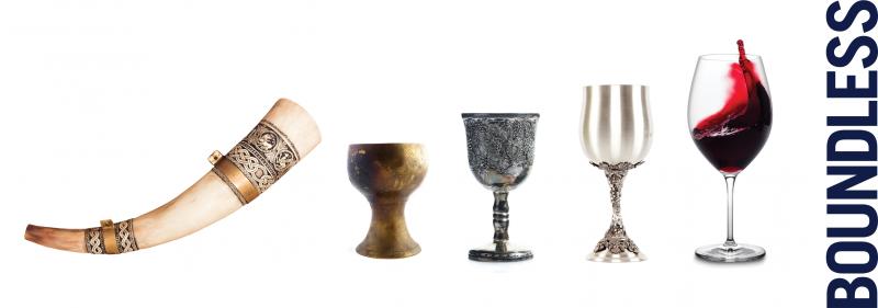 A horn wine glass, wooden goblet, pewter goblet, silver goblet, modern wine glass half-filled with red wine.