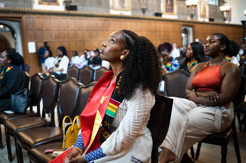 An audience of graduates in Black Grad stoles, listening to a performance.