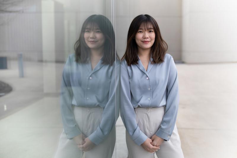 Yu-Chieh (Lily) Tsai leans on a glass wall, creating a mirror-image reflection.