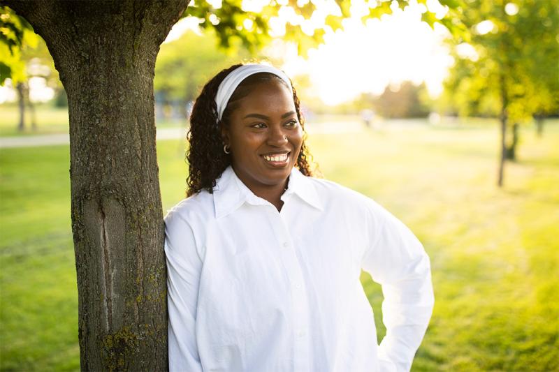 Thereasa Gordon leaning on a tree and smiling.