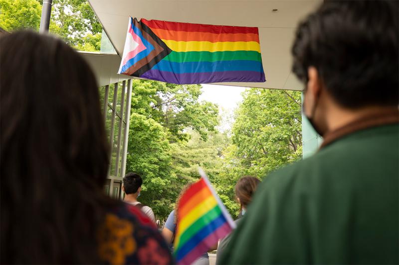 The Progress Pride flag hangs from a porch roof.