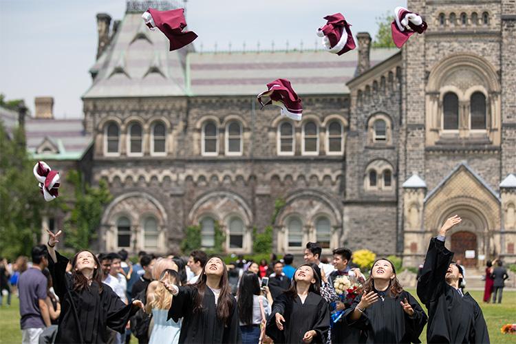 Graduates toss their hoods high in the air, with University College in the background.