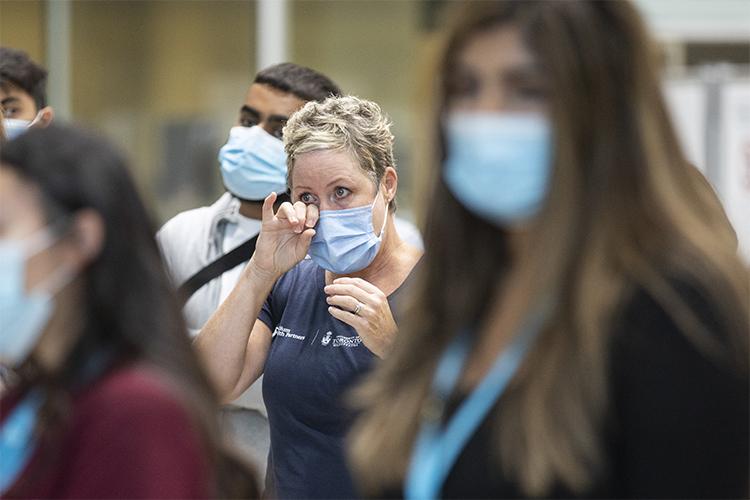 A woman wipes away a tear as she stands among masked clinic workers listening to a speech.