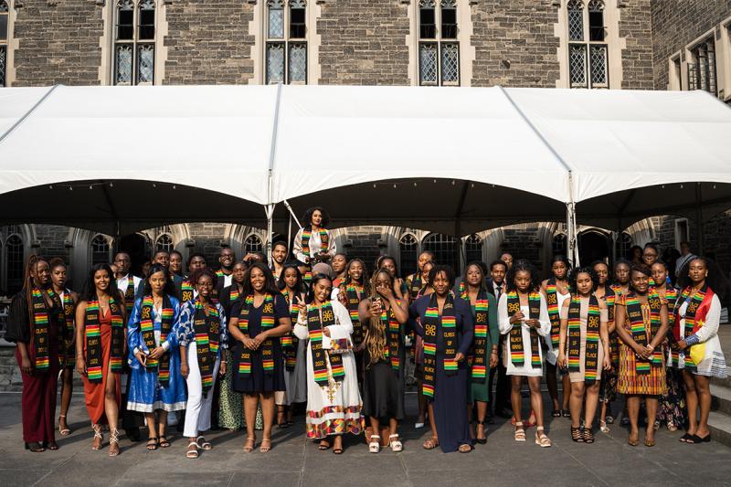 More than 40 graduates pose for a group picture in front of Hart House.