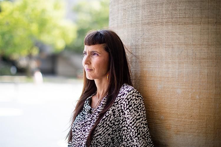 Suzanne Stewart looks thoughtful as she leans on a pillar outside Convocation Hall.