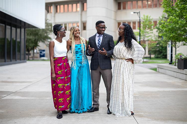 Barakat Omotosho, Kalkidan Alemayehu, Henry Ssali and Ayaan Abdulle chat and laugh in a courtyard outside.