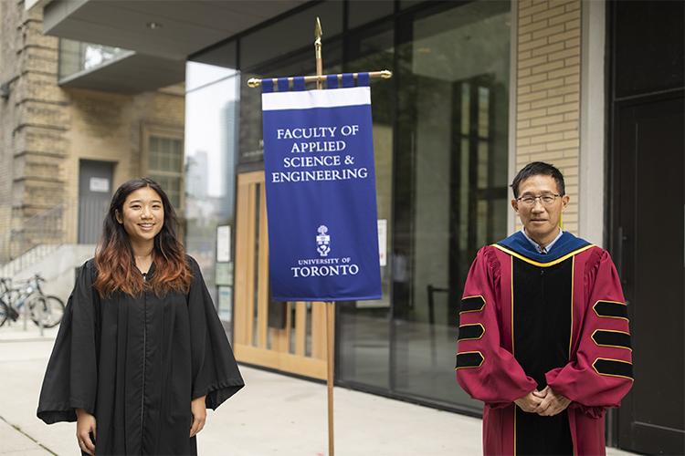Samantha Cheung and Christopher Yip wear robes and stand by a banner that reads: Faculty of Applied Science & Engineering