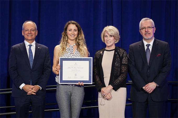 Jillian Sprenger holds her Award of Excellence while standing on stage with Meric Gertler, Rose Patten and Scott MacKendrick.