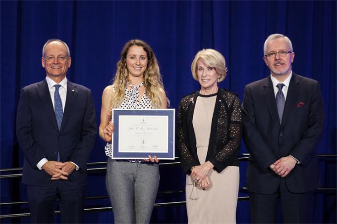 Jillian Sprenger holds her Award of Excellence while standing on stage with Meric Gertler, Rose Patten and Scott MacKendrick.