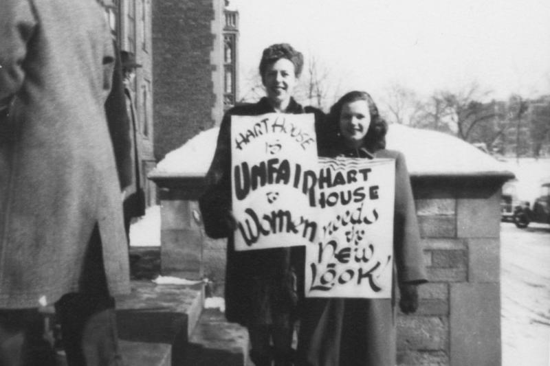 Two women hold up posters reading: Hart House is Unfair to Women and Hart House Needs the New Look.
