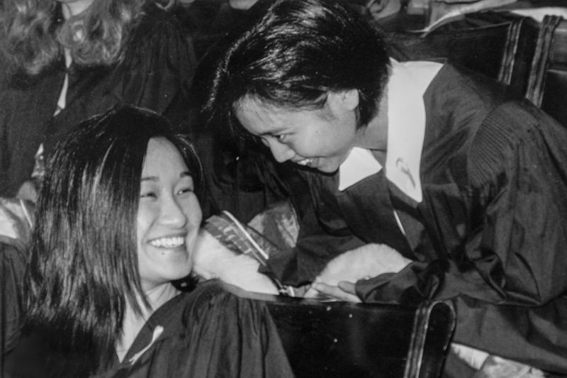 A student turns in her seat in Convocation Hall to laugh with another student standing behind her.