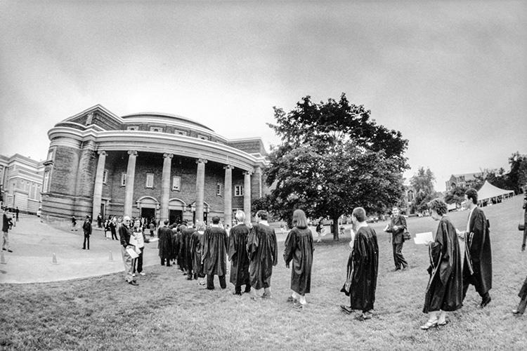 A line of students in academic gowns stretches across Front Campus.