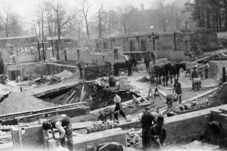On the Hart House construction site, workers transfer stones from horse-drawn carts into wheelbarrows.