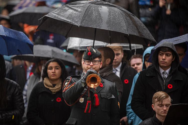 Cpl. Jonathan Elliotson plays The Last Post while attendees on the downtown Toronto campus look on (photo by Nick Iwanyshyn)