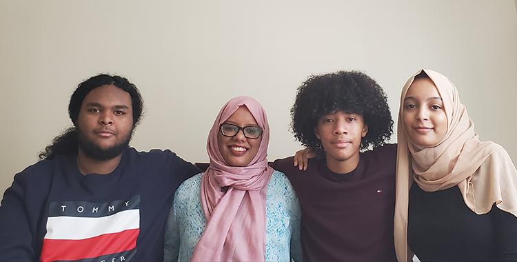 Mariam Abeid's three grown children stand by her side with their arms around her.