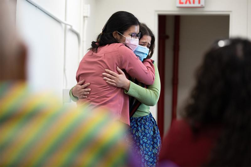 Kristine Keon and Angelique Belcourt, both wearing masks, embrace in tears.