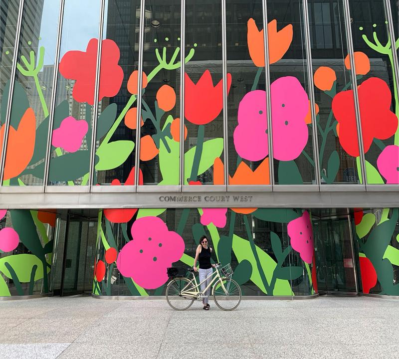 Alanna Cavanagh standing in front of an office building that she painted with colourful flowers 