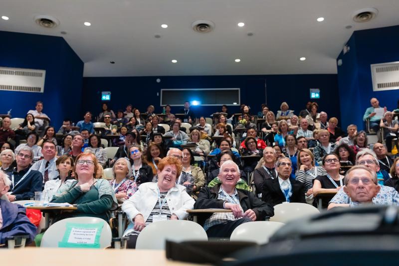 Audience of seated alumni looking amused and amazed at a lecture