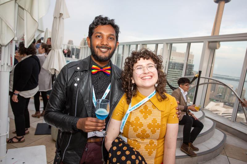 Two young alum standing side by side on outdoor patio, smiling