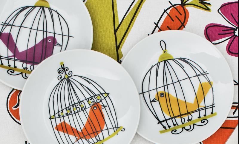 Plates featuring illustrations of birds in cages by Alanna Cavanagh