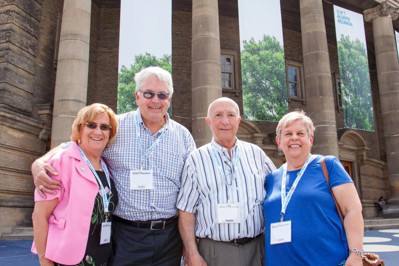 Photo of 4 alumni posing together in-front of Con Hall.