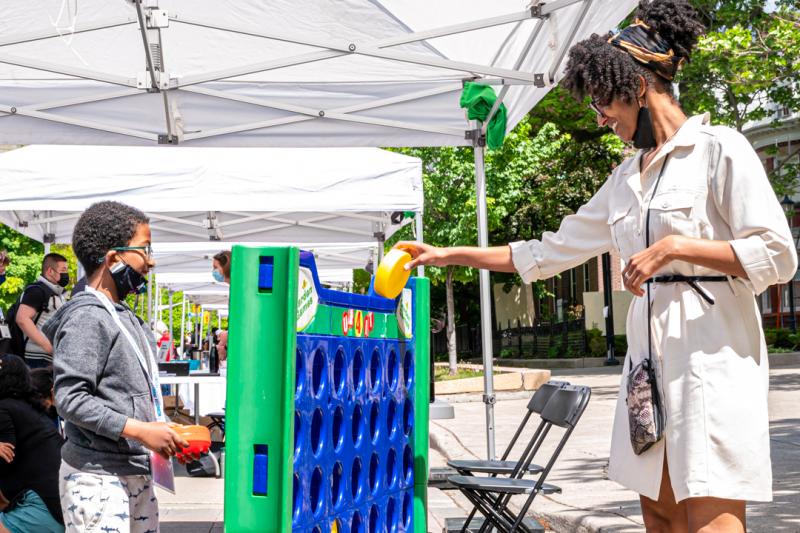 A woman smiles as she shows a small boy how to place a plastic puck into a game display.