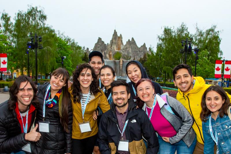 A group of people lean in for a happy group photo in front of the artificial mountain at Canada's Wonderland.