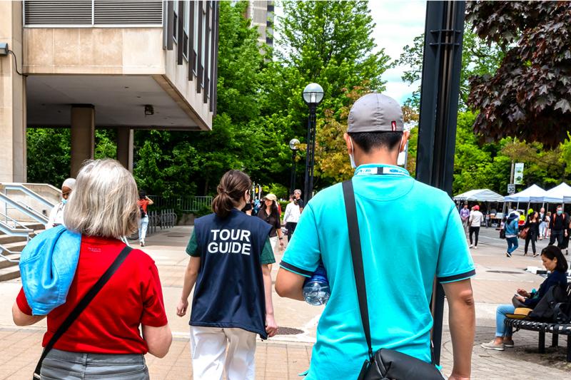 A woman in a tour guide vest leads people towards a street party.