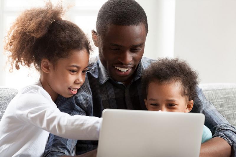 Two kids and their father looking at the computer together