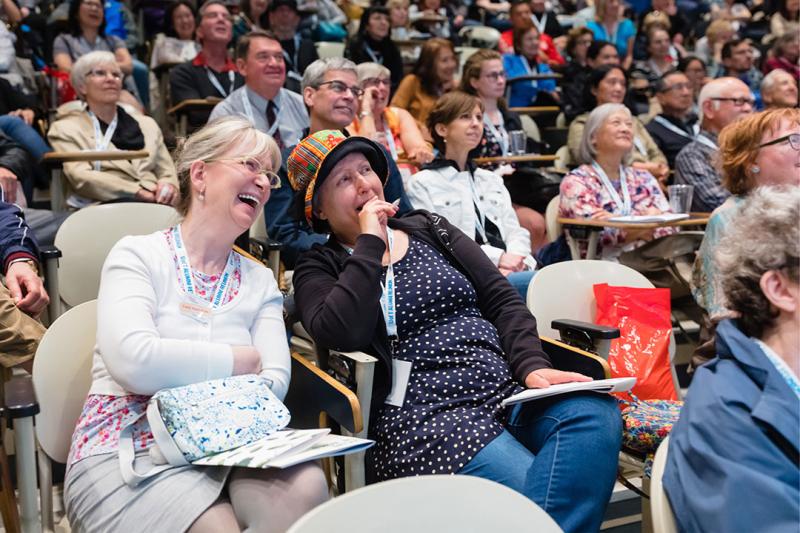 Two alumni walking laughing together at a lecture.