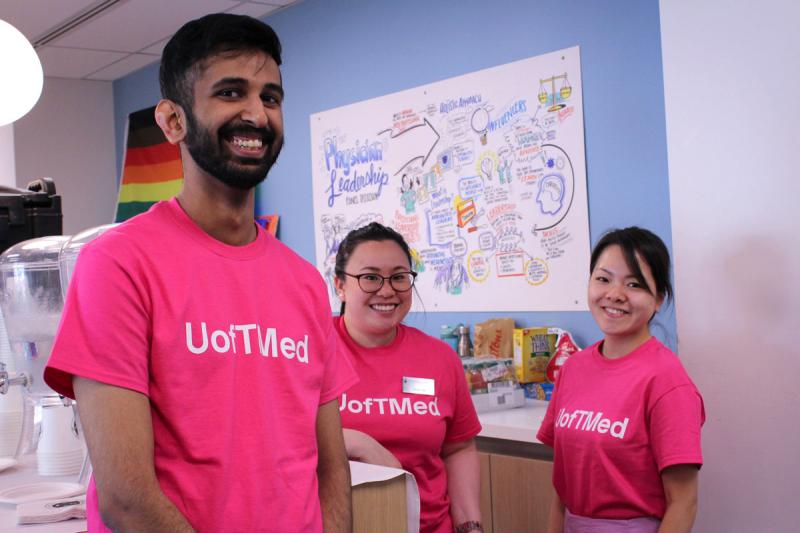 Three volunteers in U of T Med T-shirts welcome Medicine alumni to a Physician Leadership event.