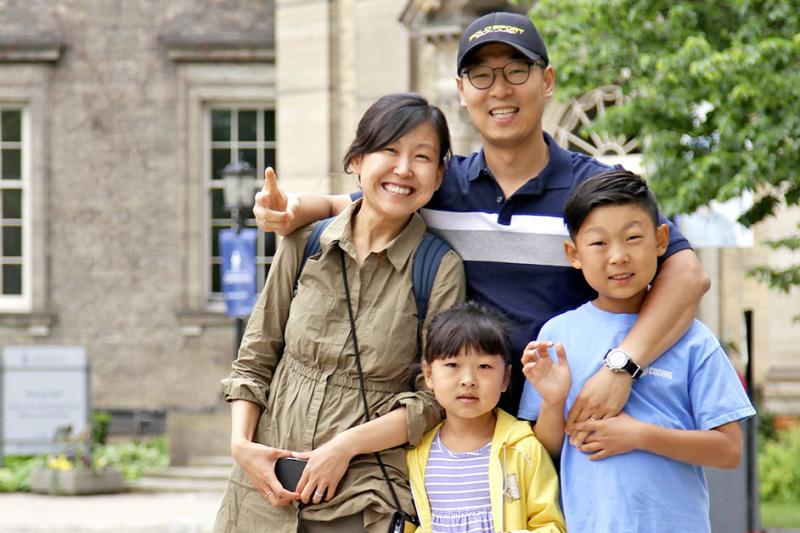 A mother, father and two children smile and pose together.