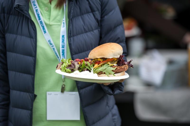 Alumni holding a burger.