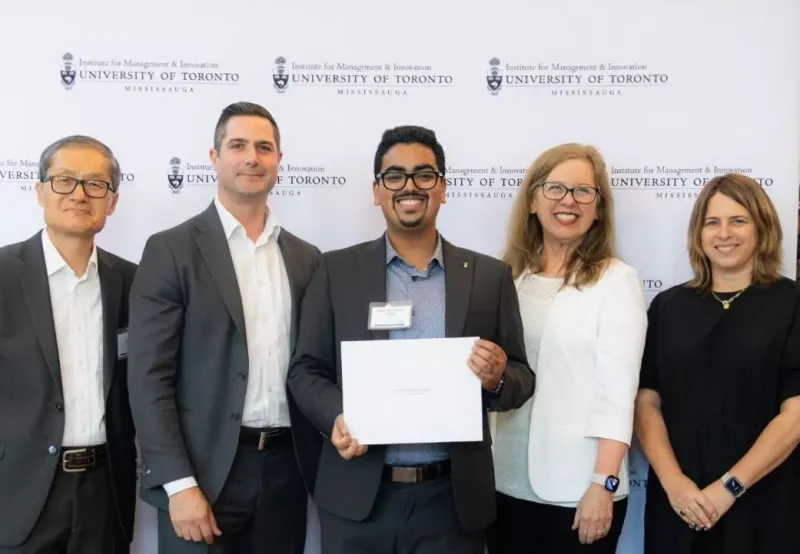 Amit Dalaya holding an award with a group of people