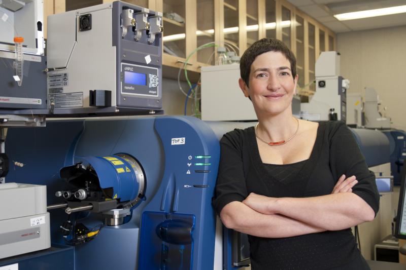 Anne-Claude Gingras smiles as she leans on a massive scientific machine.