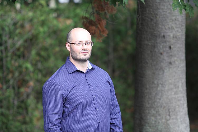 Ashkan Beigi stands under a tree outdoors.