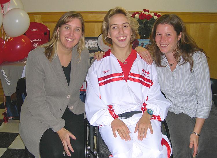 Kaley McLean, in Team Canada gear, smiles as she sits between Tina Doyle and Laurie Wright.