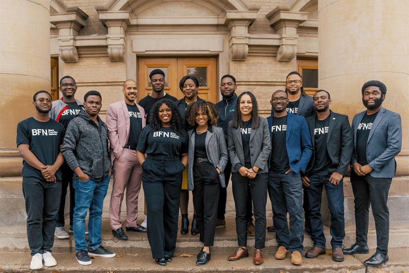 14 young Black entrepreneurs in BFN T-shirts pose on the steps of Convocation Hall.