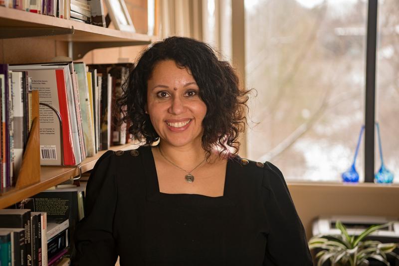 Karina Vernon smiles as she sits in a book-lined office.