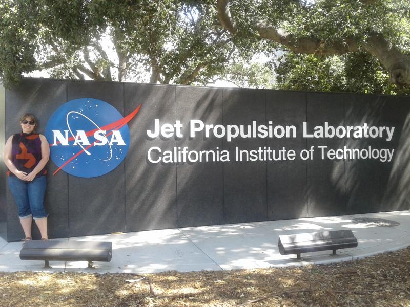 Camilla Urbaniak standing in front of the NASA Jet Propulsion Laboratory sign.