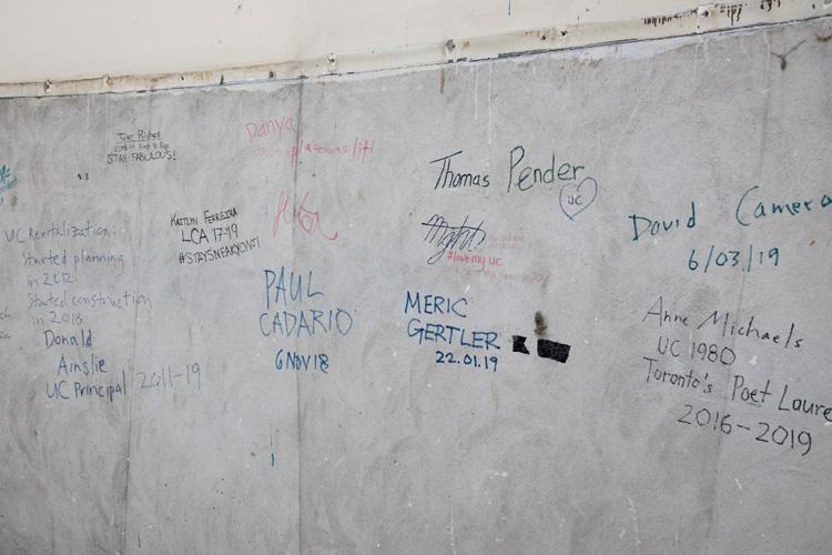 A sheet of drywall is covered with signatures, including the signature of U of T President Meric Gertler.