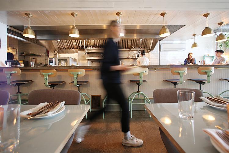 A waiter rushes past sparkling table settings at the Grey Gardens diner-style restaurant