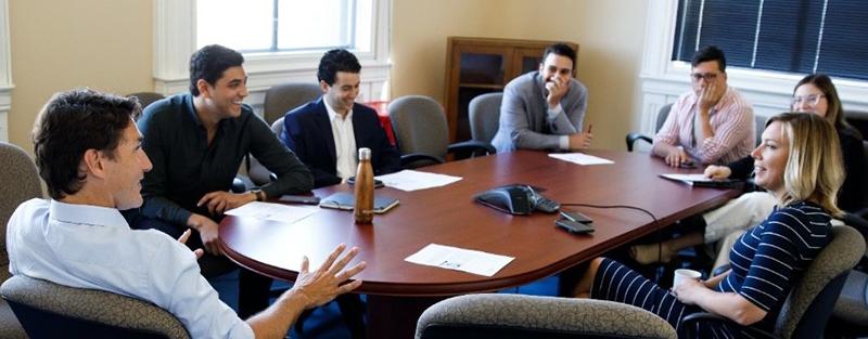 A group of people including the Prime Minister and Harry seated around a boardroom table