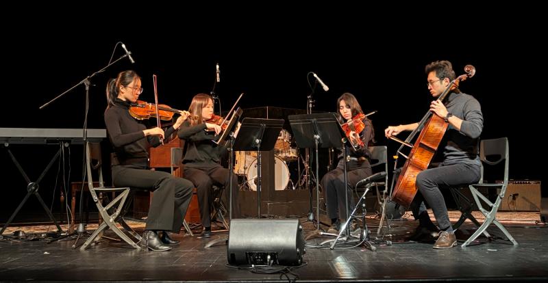 Students on stage at Hart House Theatre performing in a string quartet