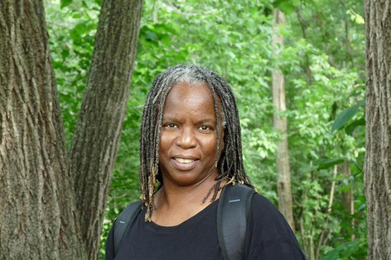 Jacqueline Scott smiles as she stands in a lush, healthy forest.