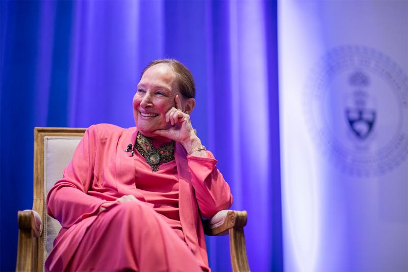 Rosalie Abella laughs, hand to chin, as she sits on stage at the Jackman Law building.