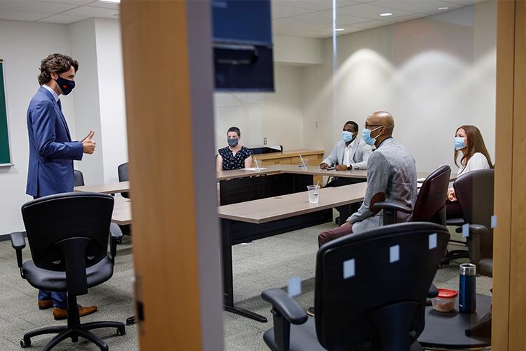 Justin Trudeau gives the thumbs up to four people sitting at a conference table. Everyone wears a mask.