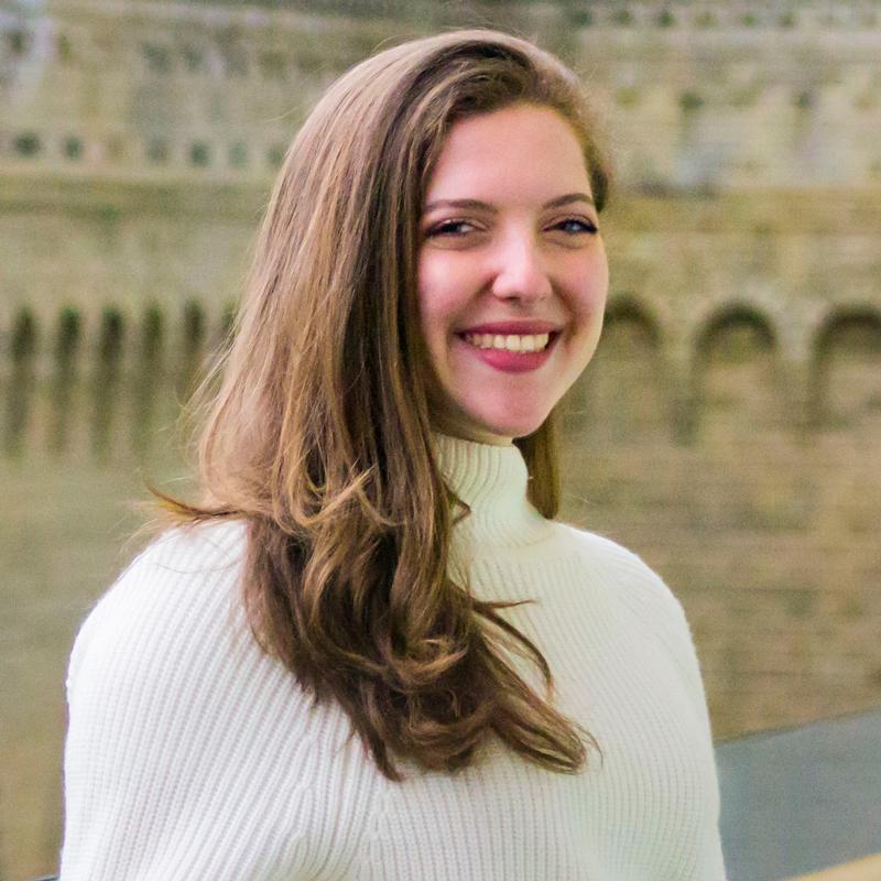 Lana El Sanyoura smiles while standing in a courtyard outside.